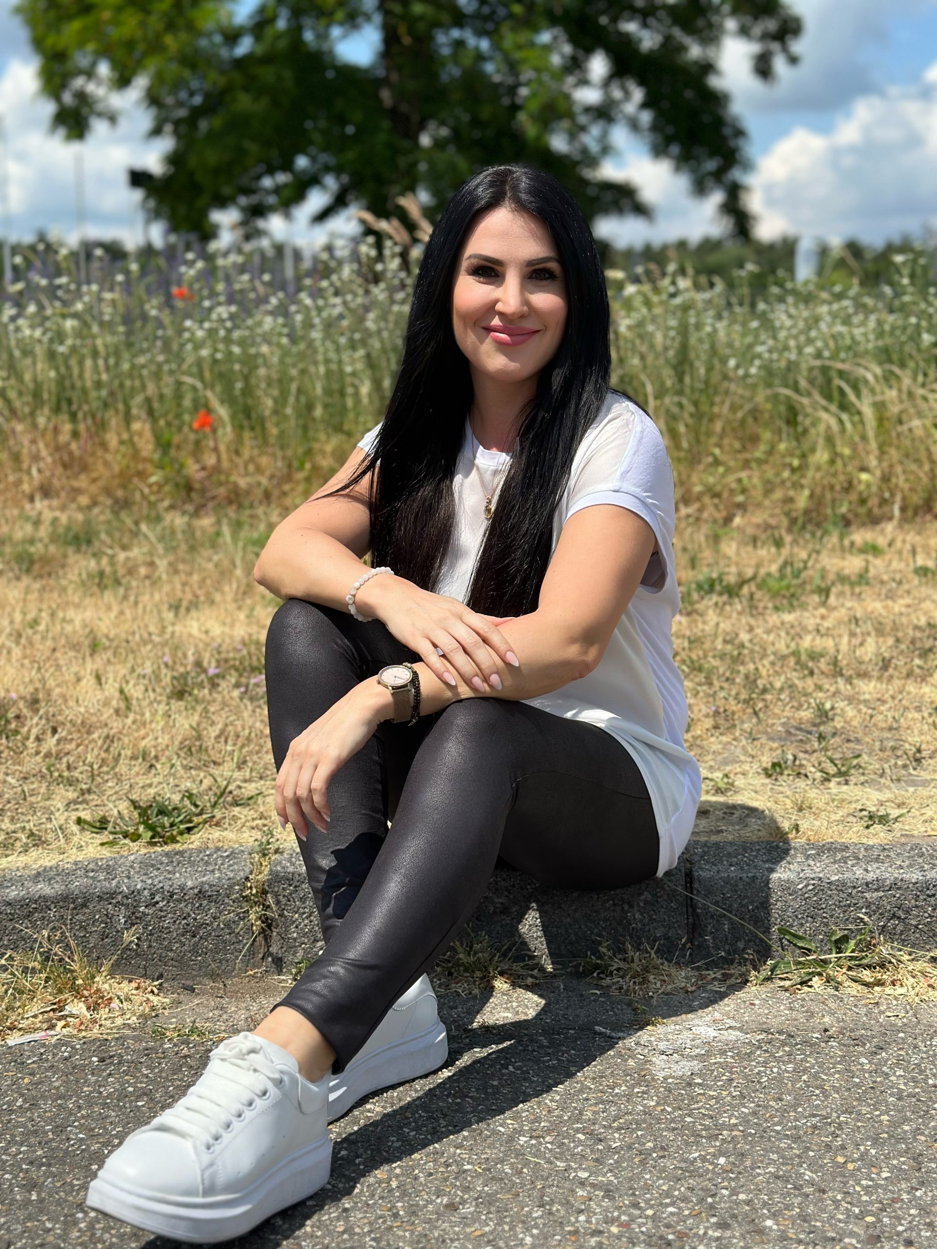 Frau sitzt in der Natur, selbstbewusst, zufrieden und glücklich auch in Beziehung